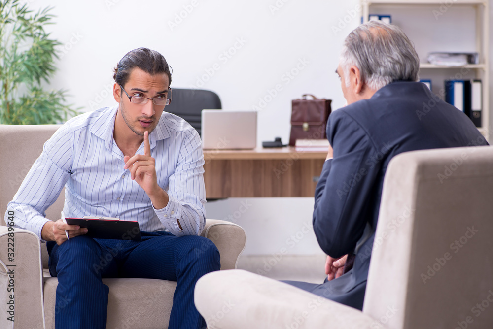 Old man visiting young male doctor psychologist Old man visiting young male doctor psychologist