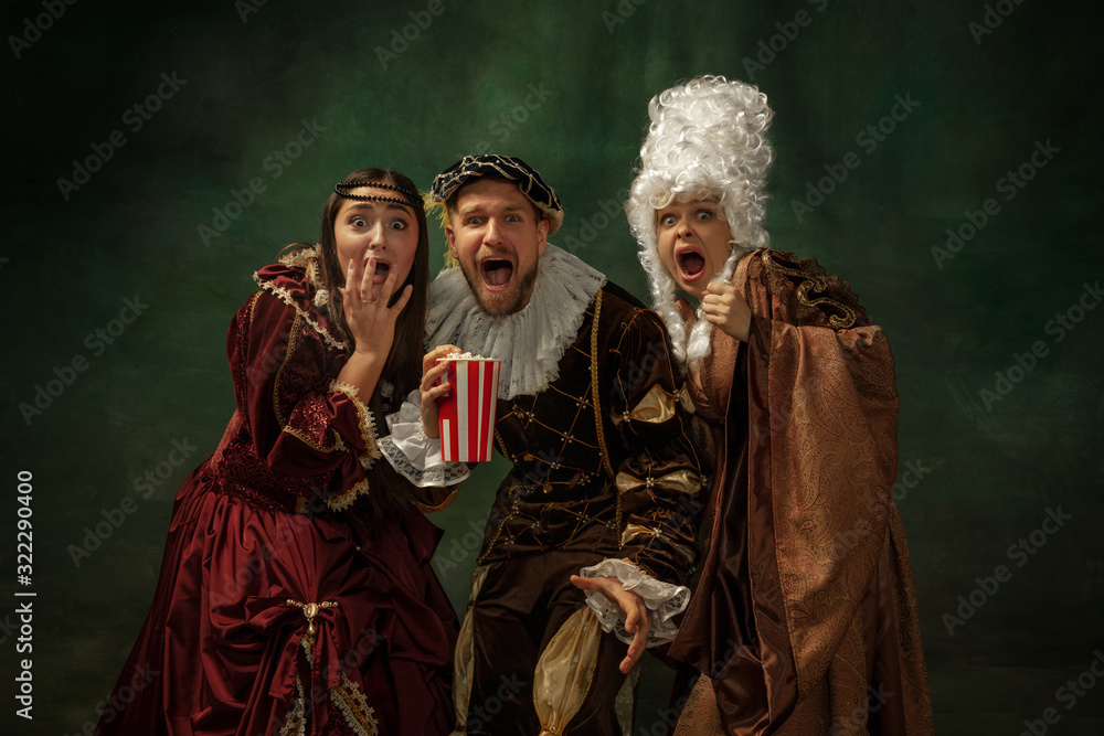 Emotional horror. Portrait of medieval young people in vintage clothing on dark background. Models as a duke and duchess, princess, royal persons. Concept of comparison of eras, modern, fashion. Emotional horror. Portrait of medieval young people in vintage clothing on dark background. Models as a duke and duchess, princess, royal persons. Concept of comparison of eras, modern, fashion.