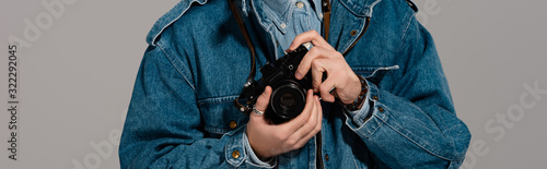 panoramic shot of man in denim jacket holding digital camera isolated on grey © LIGHTFIELD STUDIOS