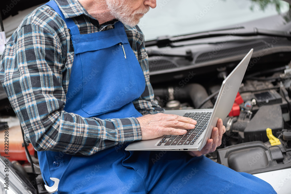 Obraz premium Mechanic using laptop for checking car engine
