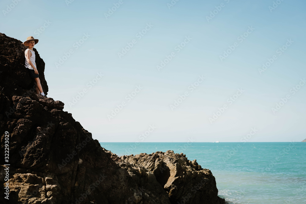 Two young boys climbing rocks by the beach at Coral Beach near Shute Harbour in the Whitsundays, Queensland Australia