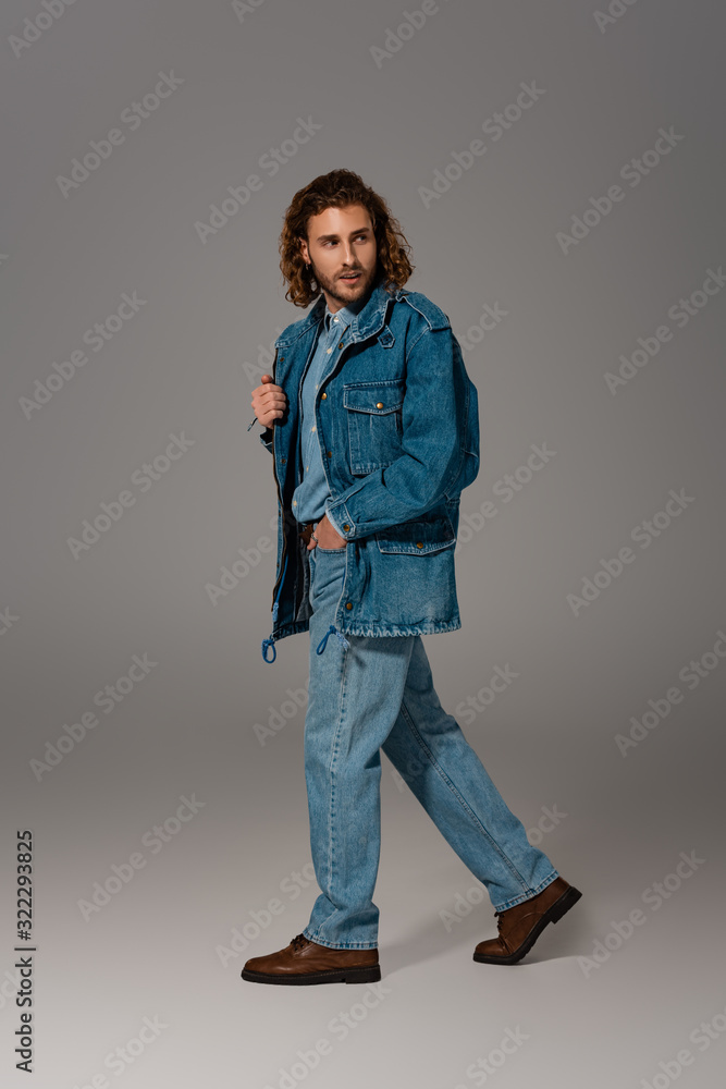 Fototapeta premium handsome and stylish man in denim jacket and jeans looking away on grey background