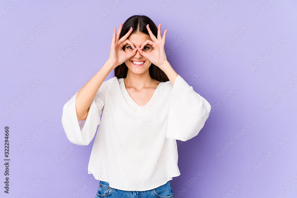 Young caucasian woman isolated on purple background excited keeping ok gesture on eye. Young caucasian woman isolated on purple background excited keeping ok gesture on eye.