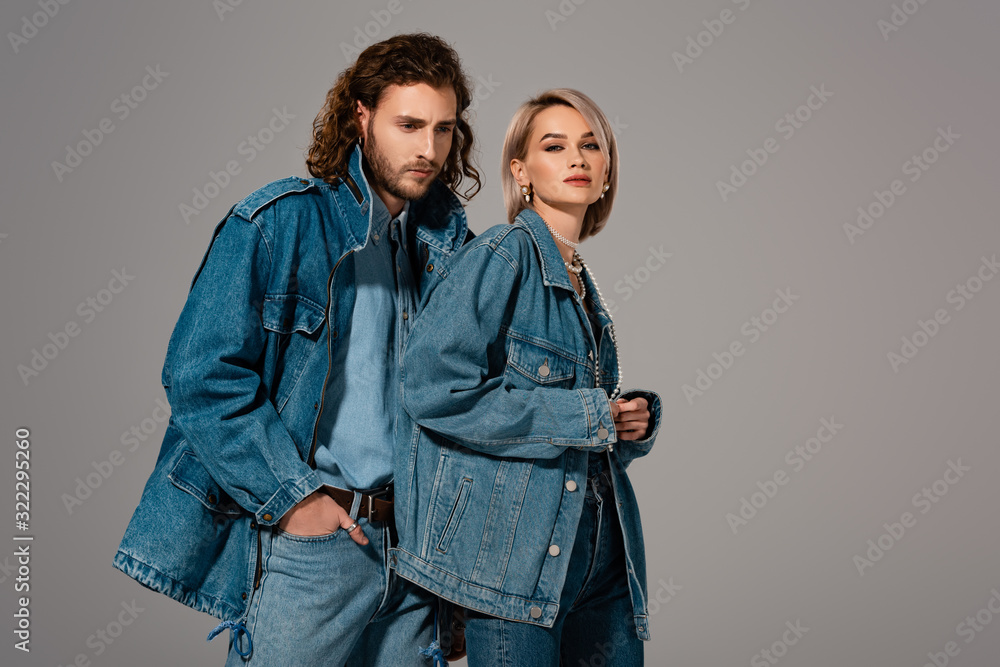 stylish man and woman in denim jackets looking at camera isolated on grey stylish man and woman in denim jackets looking at camera isolated on grey