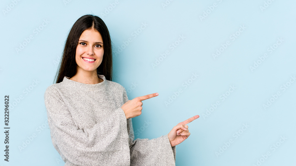 Young caucasian woman isolated on blue background excited pointing with forefingers away. Young caucasian woman isolated on blue background excited pointing with forefingers away.