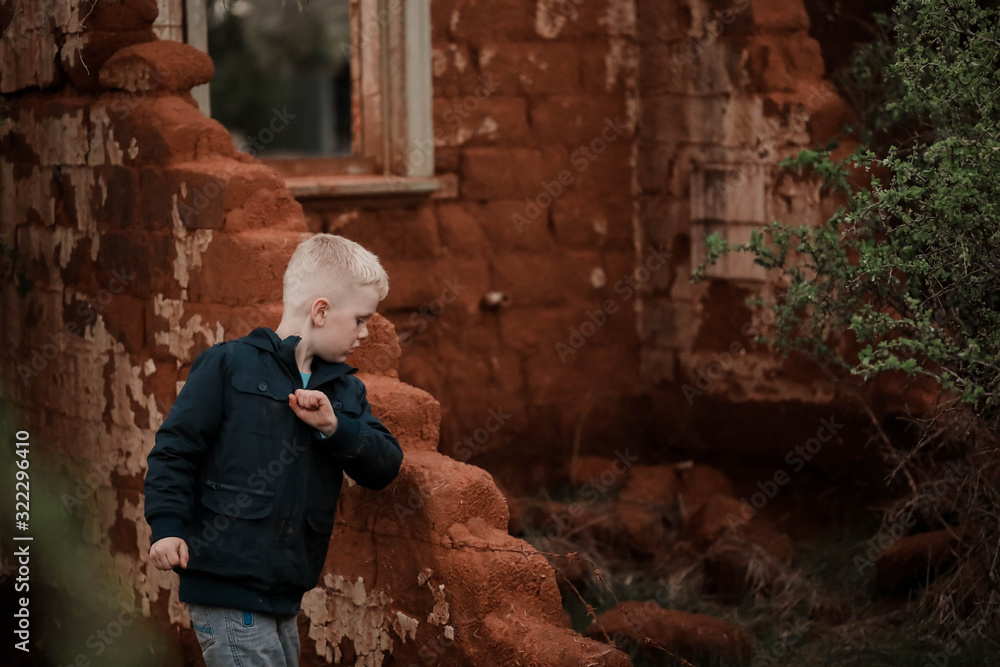 Young boy exploring ruins of fallen down mud brick house