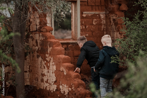 Two boys exploring ruins of fallen down mud brick house © Caseyjadew