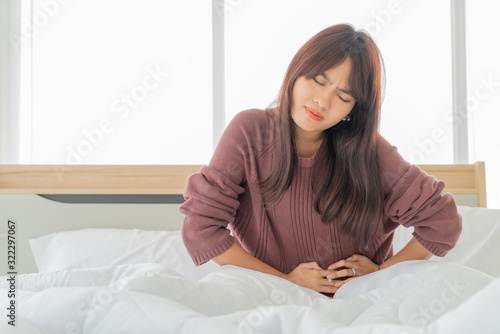 Asian women stomachache and sleeping on bed