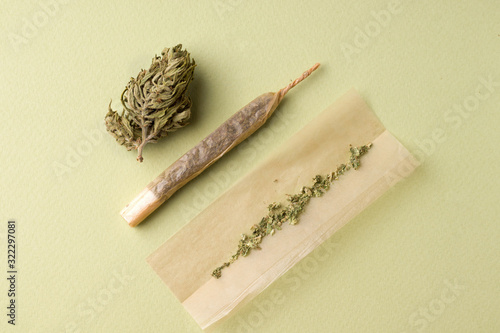 the process of making a roll of cigarettes with marijuana on a green background photo