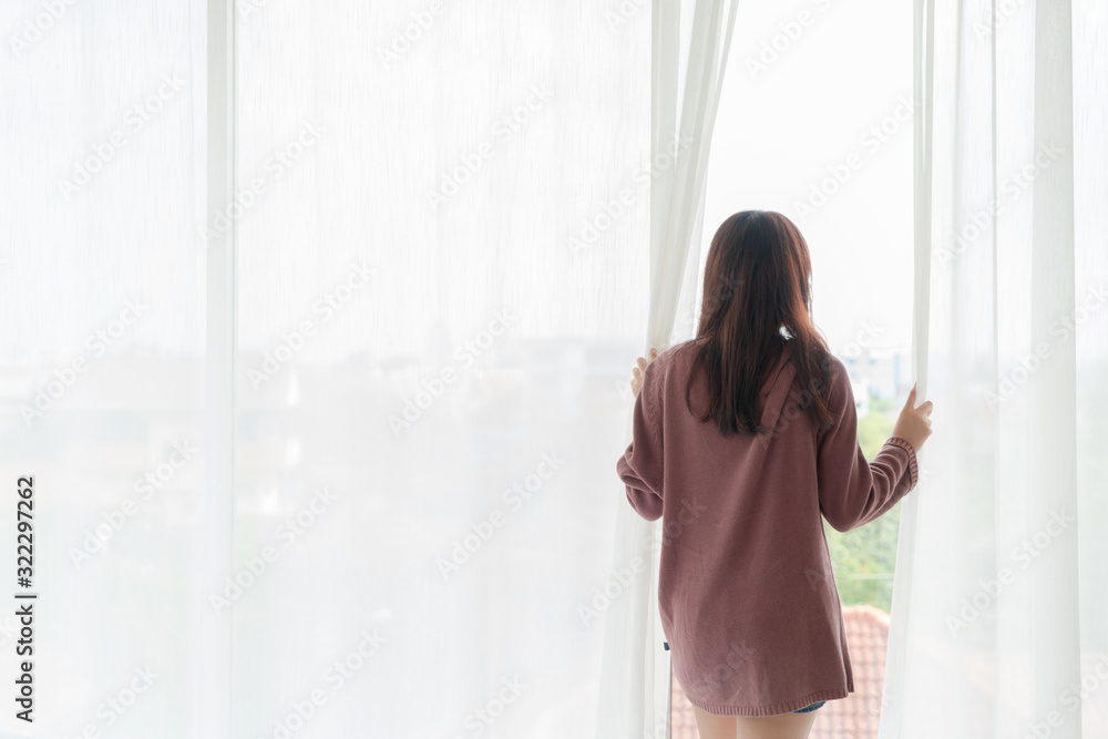 Asian women open the curtain in the morning