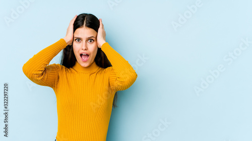 Young caucasian woman isolated on blue background screaming, very excited, passionate, satisfied with something. © Asier