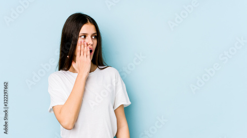 Young caucasian woman isolated on blue background being shocked because of something she has seen.