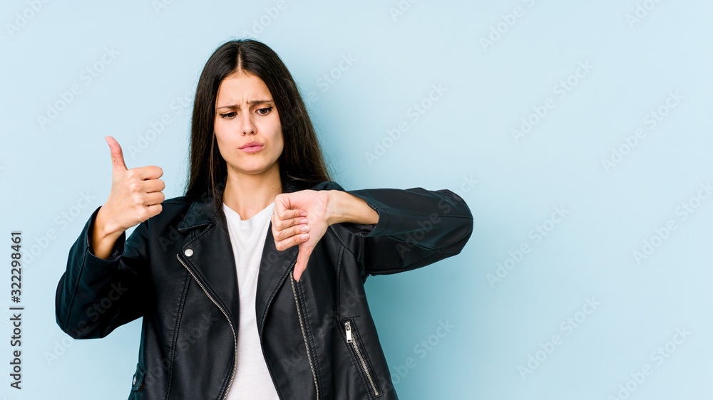 Young caucasian woman isolated on blue background showing thumbs up and thumbs down, difficult choose concept Young caucasian woman isolated on blue background showing thumbs up and thumbs down, difficult choose concept