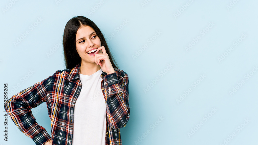 Young caucasian woman isolated on blue background relaxed thinking about something looking at a copy space.