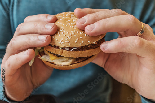 Men's hands hold a fresh tasty burger.