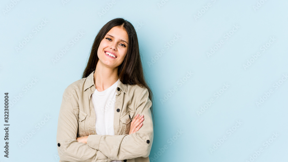 Young caucasian woman isolated on blue background who feels confident, crossing arms with determination. Young caucasian woman isolated on blue background who feels confident, crossing arms with determination.