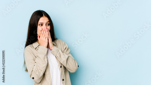 Young caucasian woman isolated on blue background laughing about something, covering mouth with hands.