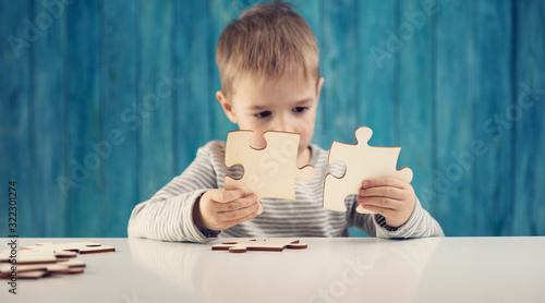 Canvas Print Little child holding puzzle pieces and trying to solve it