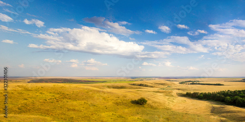 Panoramic view, aerial skyline of summer landscape of fields and meadows with harvested crop, boundless expanses, blue sky with cumulus clouds, top view from mountain