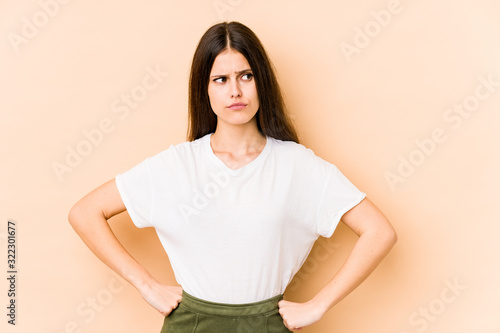 Young caucasian woman isolated on beige background confused, feels doubtful and unsure.