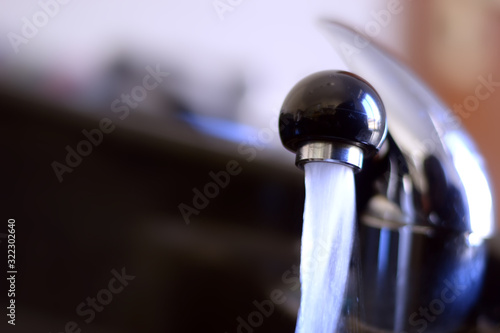 Drinking water from the tap in the sink.