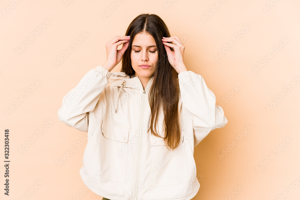 Young caucasian woman isolated on beige background touching temples and having headache. Young caucasian woman isolated on beige background touching temples and having headache.