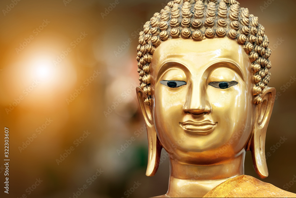 Golden buddha face on golden background at Thai temple.