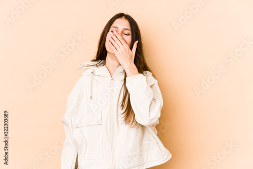 Young caucasian woman isolated on beige background laughing happy, carefree, natural emotion.