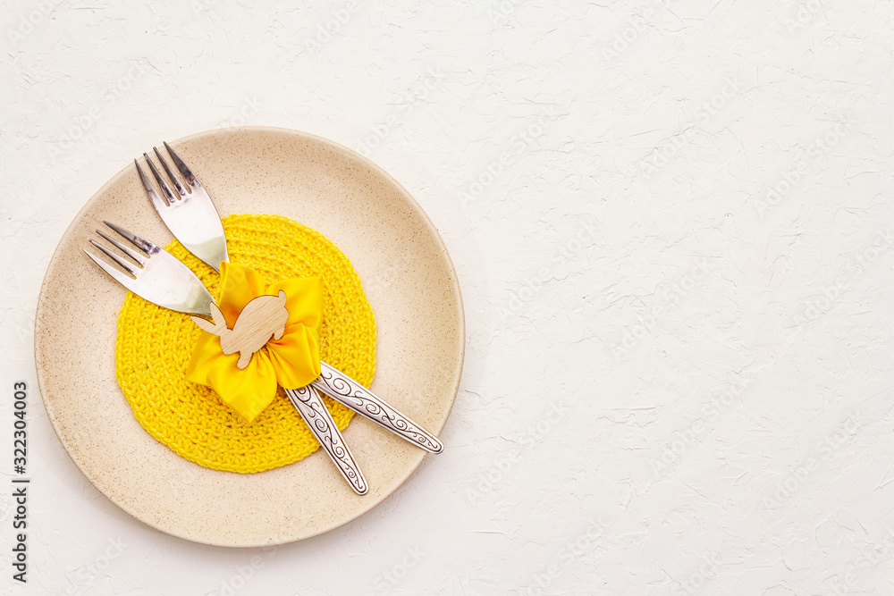 Easter table setting on textured white putty background. Spring holiday card template. Cutlery, knitted napkin, flower Easter table setting on textured white putty background. Spring holiday card template. Cutlery, knitted napkin, flower