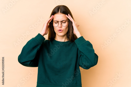 Young caucasian woman isolated on beige background touching temples and having headache. © Asier