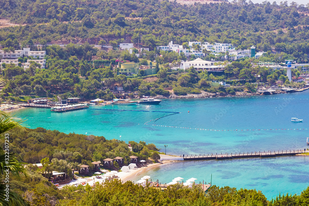 Beautiful bay with clear azure water and green palms. Beach on the territory of luxury Turkish hotel in Bodrum, Mugla, Turkey. Summer rich vacation. Travel concept