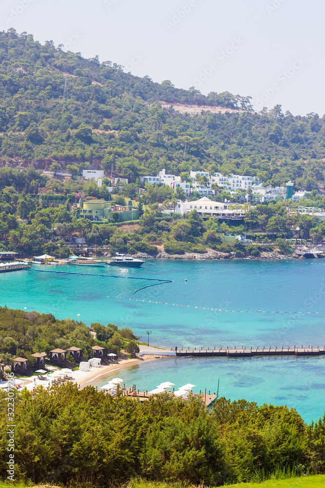 Beautiful bay with clear azure water and green palms. Beach on the territory of luxury Turkish hotel in Bodrum, Mugla, Turkey. Summer rich vacation. Travel concept