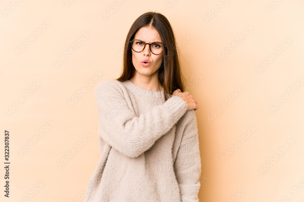 Young caucasian woman isolated on beige background having a shoulder pain. Young caucasian woman isolated on beige background having a shoulder pain.