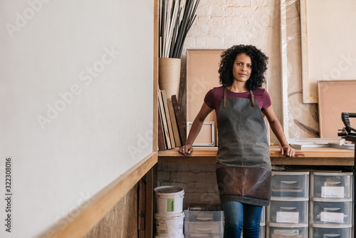 Entrepreneur leaning against a workbench in her framing studio