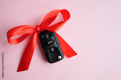 Gift car key concept with red bow on a pink background.