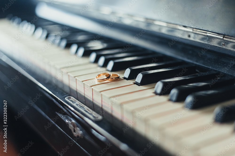 Wedding gold rings close-up on a background of black and white piano keys. Photography, concept. Wedding gold rings close-up on a background of black and white piano keys. Photography, concept.