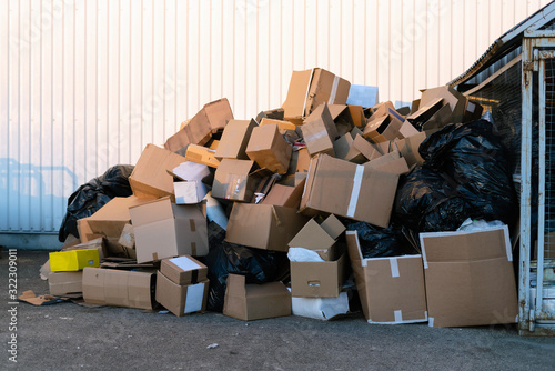 Paper boxes next to a garbage bin. Stack of paper waste outdoor in the city. Paper recycling, nobody