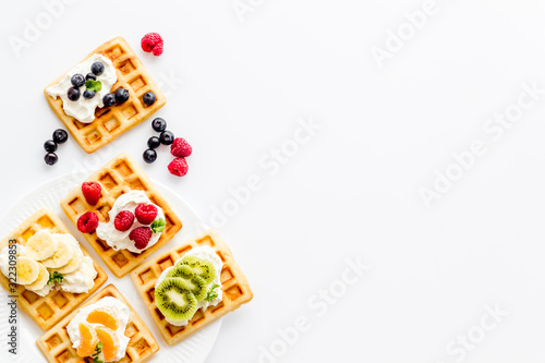 Breakfast with freashly baked belgian waffles on white background top-down frame copy space