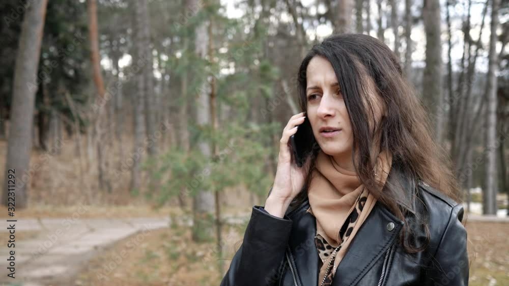 unhappy young woman is talking on phone, angry outdoors unhappy young woman is talking on phone, angry outdoors