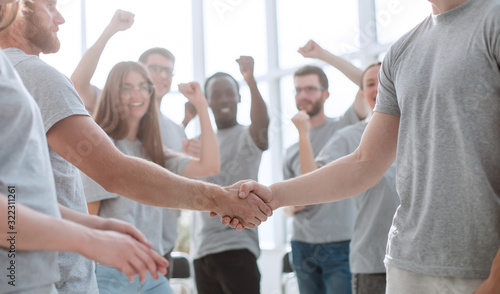 handshake of young people on the background of the jubilant team