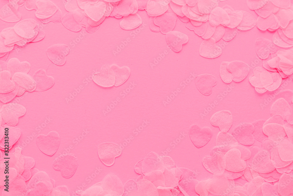 Festive romantic gentle abstract background for the design. Confetti in the shape of hearts on pink background. Top view, flat lay composition. Copy space for text.