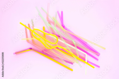Colorful plastic drinking straws on a pink background. Top view.