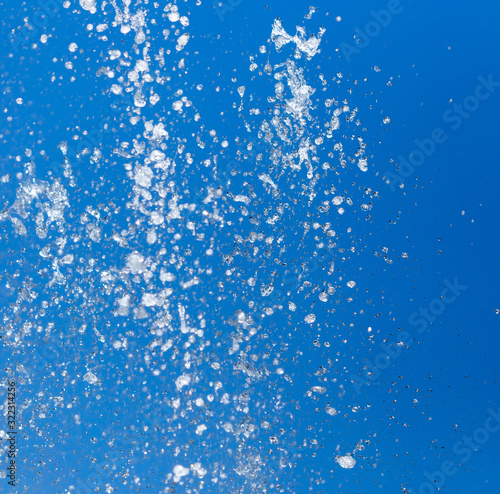 Splashing water from a fountain on a background of blue sky
