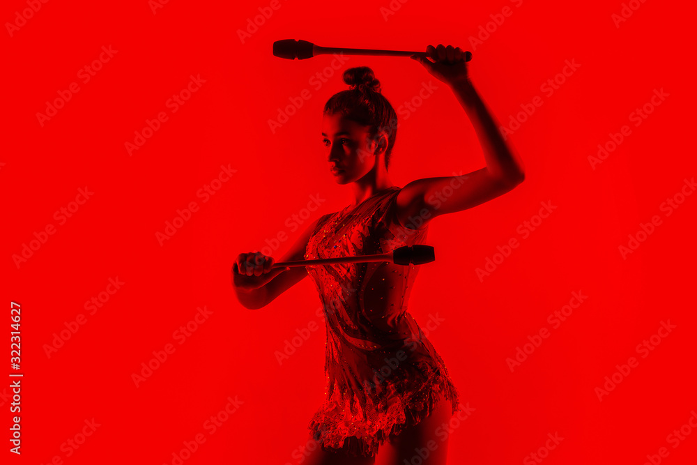 Passioned for rhythm. Young flexible girl isolated on red studio background. Teen-age female model as a gymnastics artist practicing. Exercises for flexibility, balance. Grace in motion, sport. Passioned for rhythm. Young flexible girl isolated on red studio background. Teen-age female model as a gymnastics artist practicing. Exercises for flexibility, balance. Grace in motion, sport.