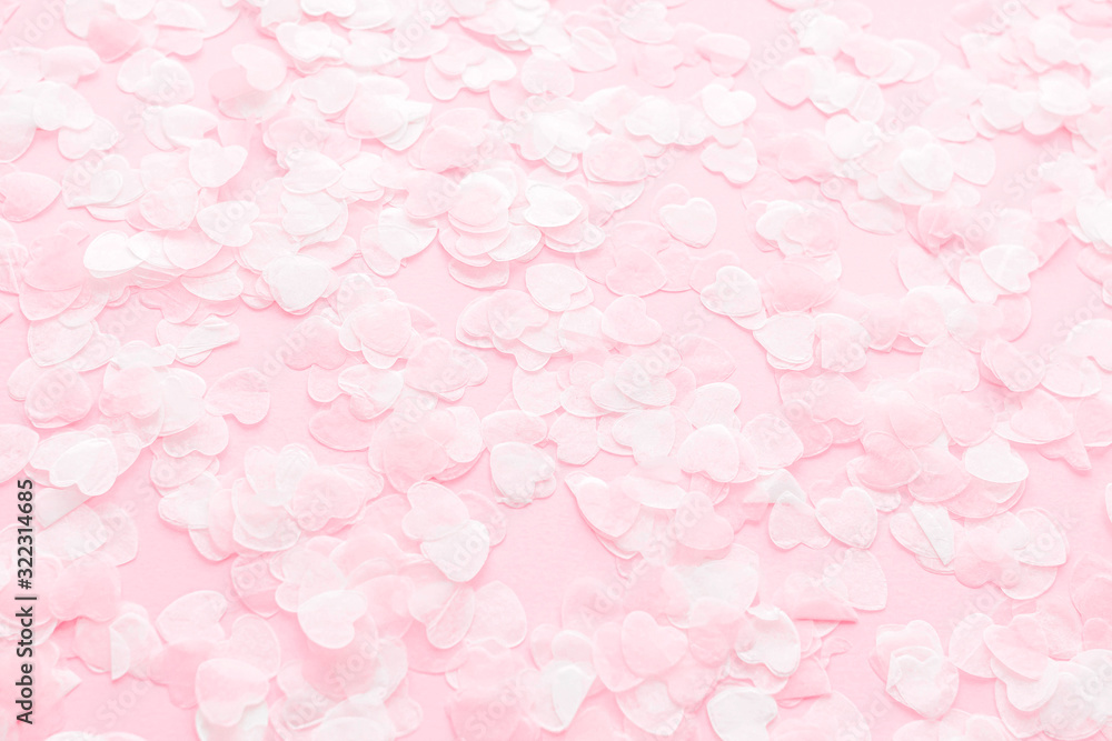 Festive romantic gentle abstract background for the design. Pink confetti in the shape of hearts on pastel background. Top view, flat lay composition. Copy space for text.