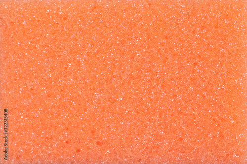 background texture of a orange sponge with shiny particles. close-up of a porous sponge