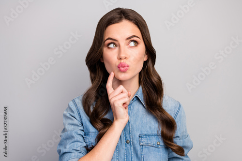 Closeup photo of pretty cute girlish curly lady hold finger on chin look up empty space dreamer send air kiss shy wear casual jeans shirt isolated grey color background
