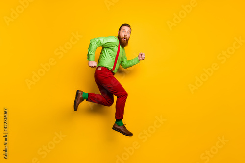 Full body profile side photo of astonished man jump run hurry incredible discounts stare stupor wear suspenders trousers isolated over shine color background © deagreez