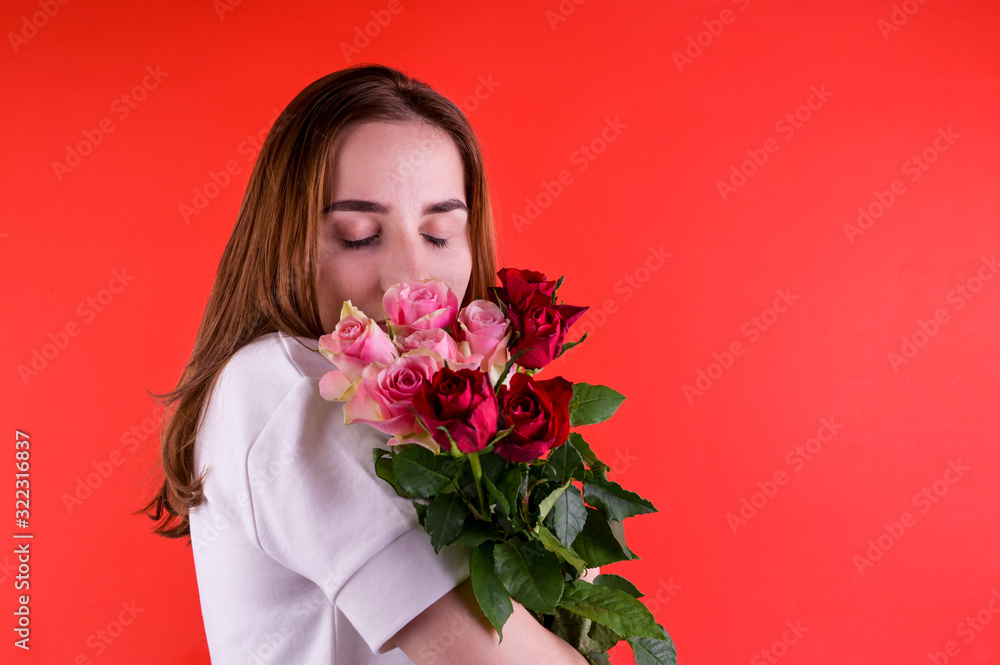 The concept of Valentine's Day and Women's Day. Happy young girl holding a bouquet of roses. A romantic gift.