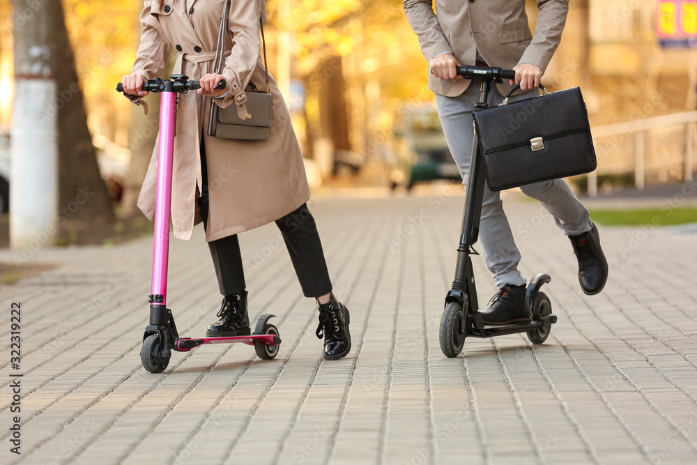 Fototapeta premium Young couple riding kick scooters outdoors